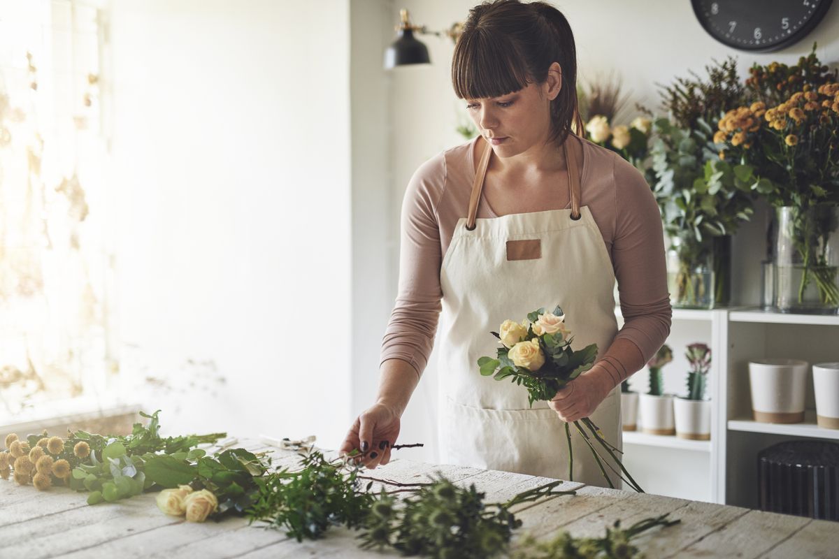 Florista montando um arranjo no balcão da própria loja